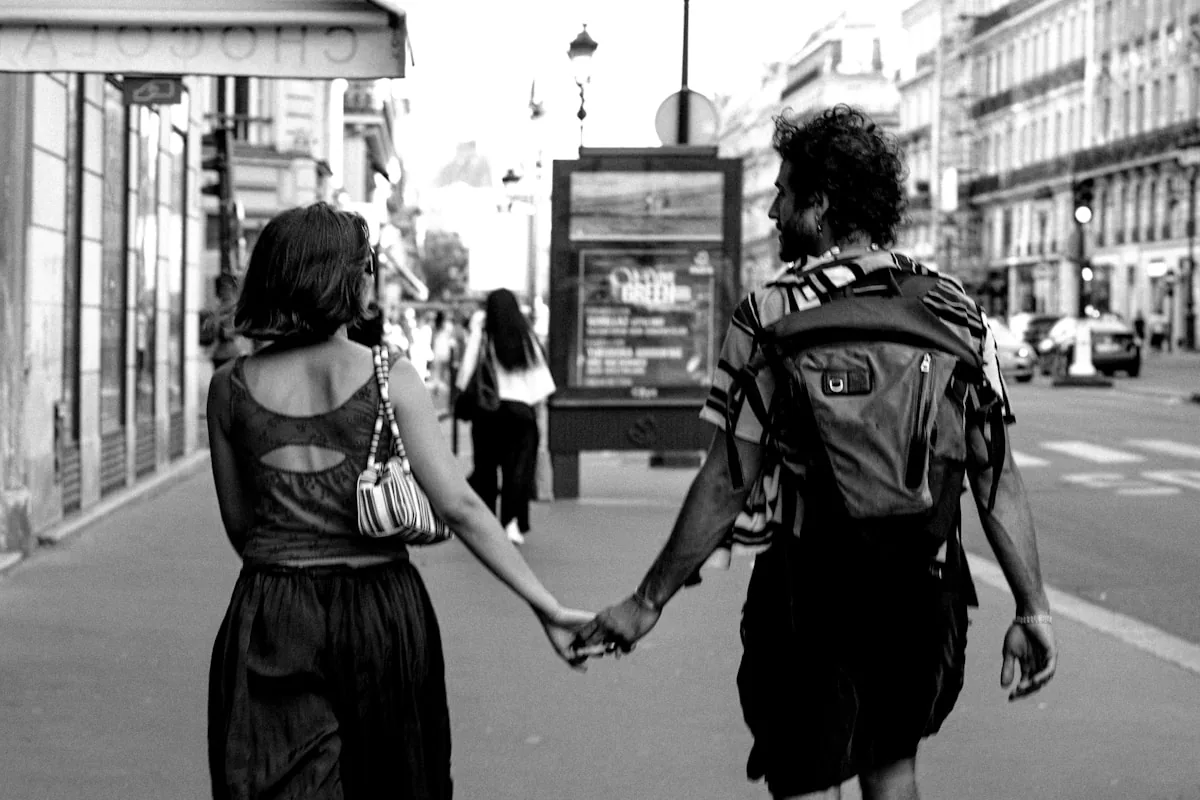 Man and woman holding hands walking on city street